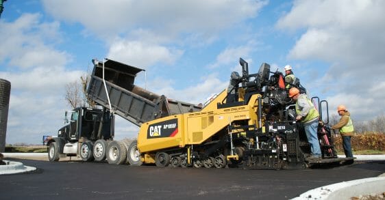 three men in hard hats working on a Cat machine