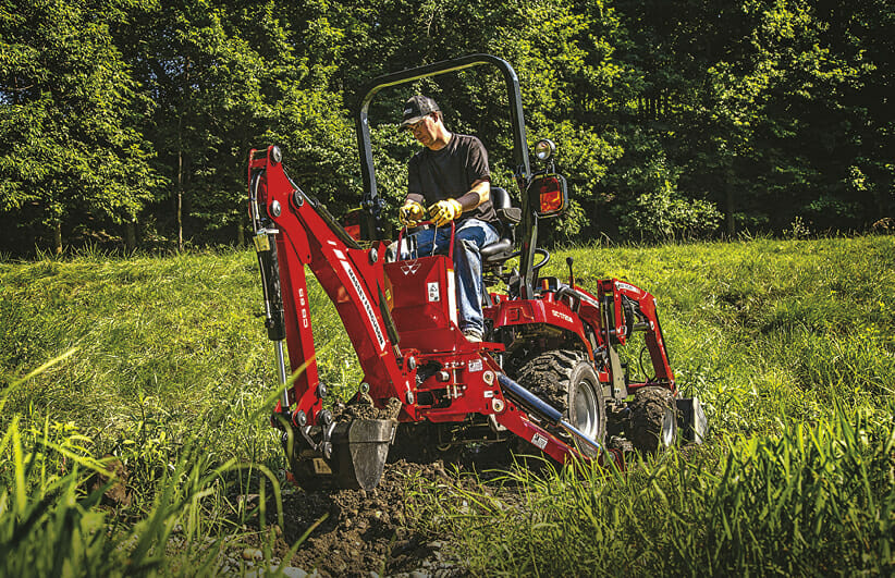 man riding a red massy ferguson sub compact tractor in a field