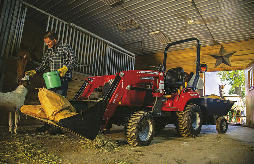 man feeding a dog in the barn with a massy ferguson tractor holding the dog food bags